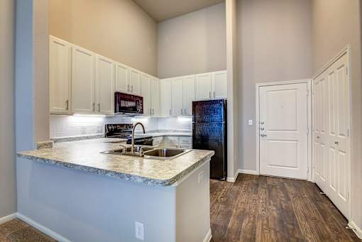 A kitchen with a granite countertop and white cabinets.