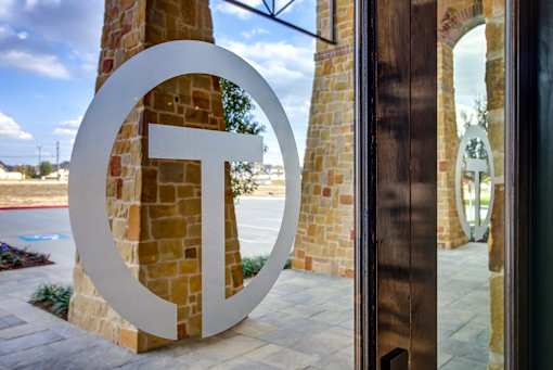 A large white letter T is in front of a building.