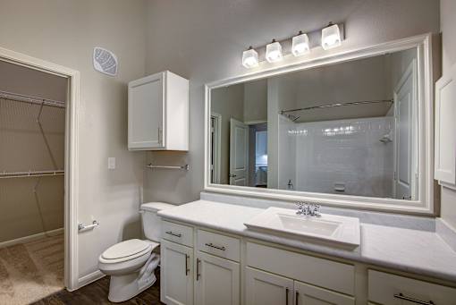 A bathroom with a toilet, sink, and mirror.