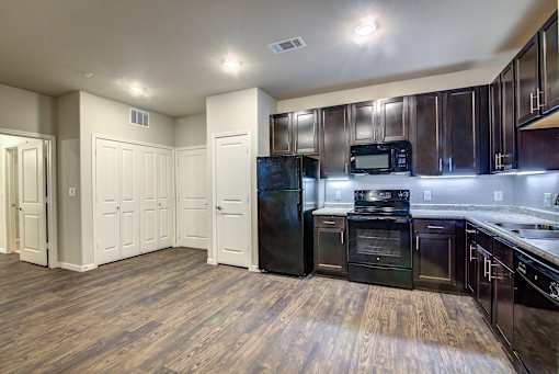A kitchen with wooden floors and black appliances.