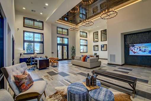 A large, well-lit living room with a variety of seating options and a flat-screen TV.