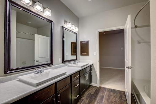 A bathroom with a sink, mirrors and lights.