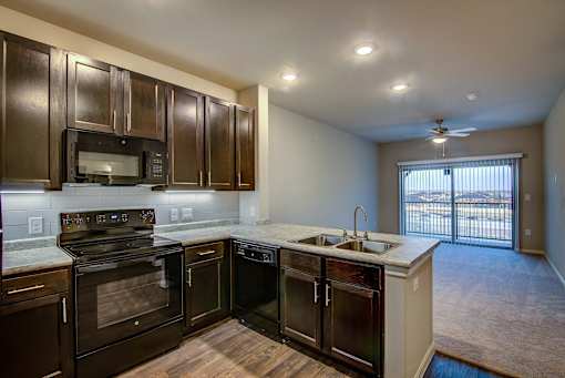 A kitchen with dark brown cabinets and black appliances.