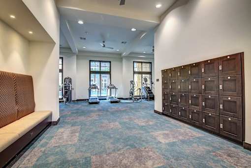 A gym with a bench, exercise equipment, and lockers.