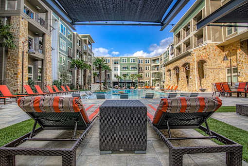 A patio with orange chairs and a table with a glass top.