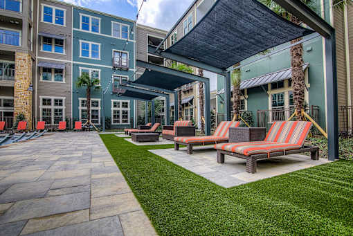 A patio area with a striped couch and a tree.