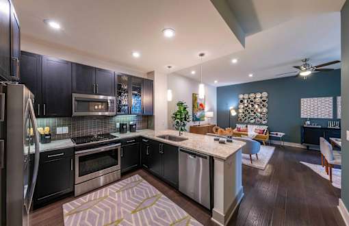 A modern kitchen with dark wood cabinets and stainless steel appliances.