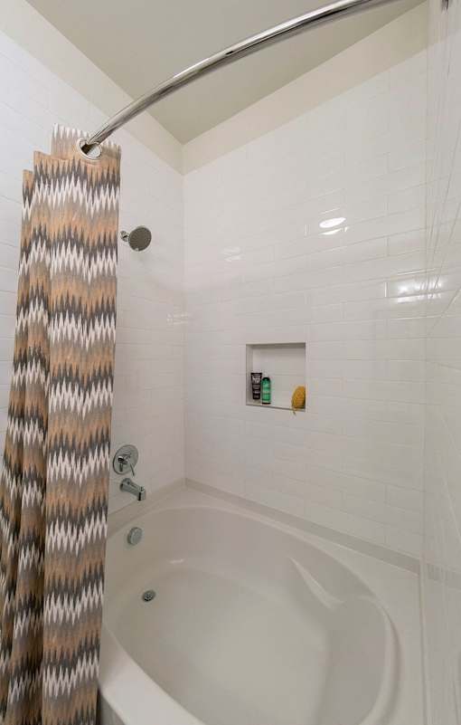 A white bathtub with a shower curtain on the left.
