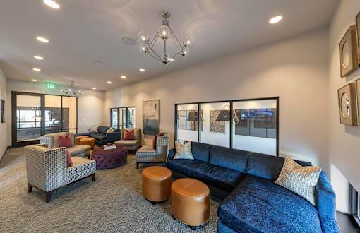 A living room with a blue couch and a brown ottoman.