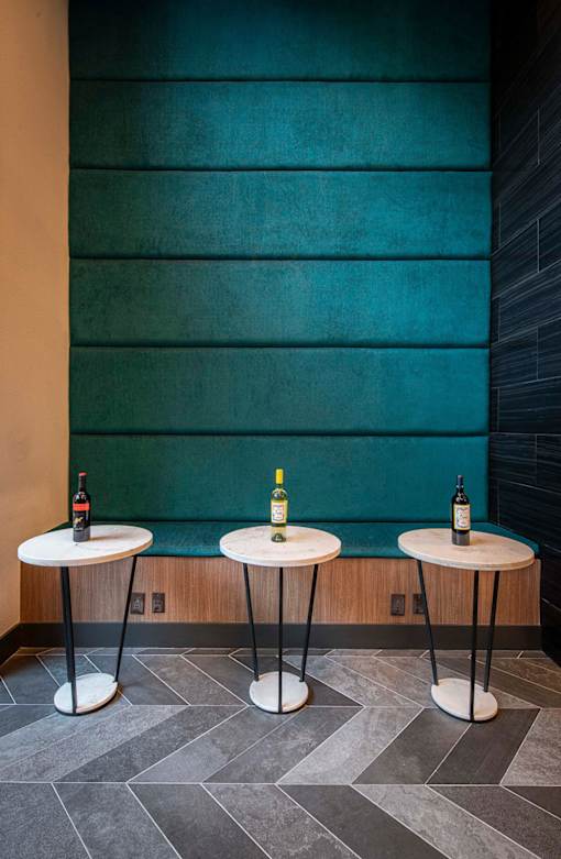 Three small tables with wine bottles on them.