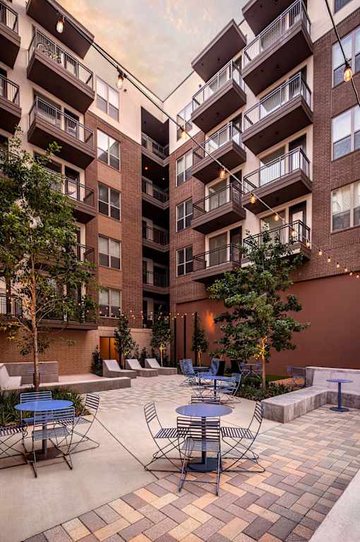 A courtyard with tables and chairs surrounded by apartment buildings.