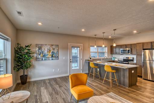 A modern kitchen with a yellow chair and a wooden floor.