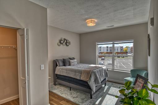 A bedroom with a bed, chair, and window.