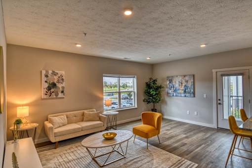 A living room with a white couch, a yellow chair, and a white coffee table.