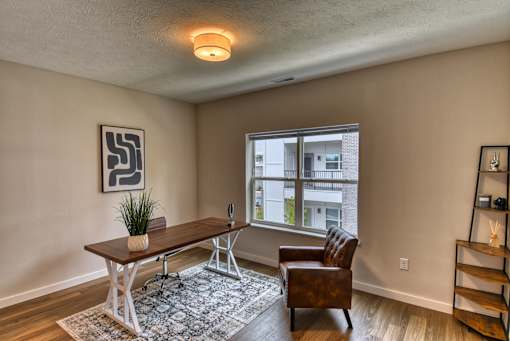 A room with a brown chair and a table with a potted plant on it.