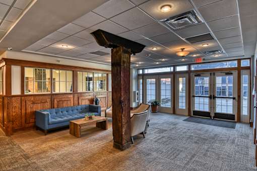 A large room with a blue couch and a wooden pillar.