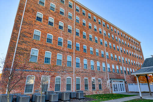 A tall red brick building with many windows and a small white building to the right.