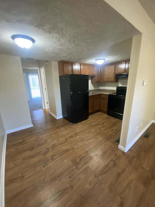 Kitchen and living room with wooden floors and a black refrigerator
