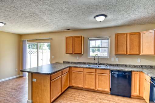 A kitchen with wooden cabinets and black countertops.