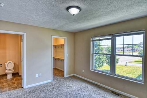 A room with a toilet and a window overlooking a street.