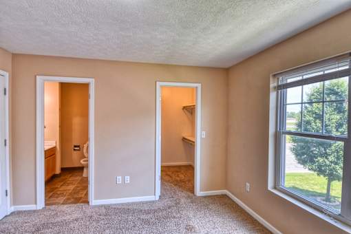 A room with a window, a door, and a carpeted floor.