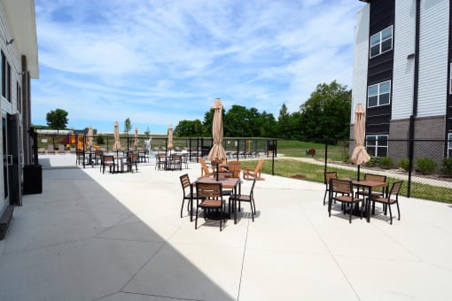 Outdoor patio area with tables and chairs  at The Landing Apartments, Indiana