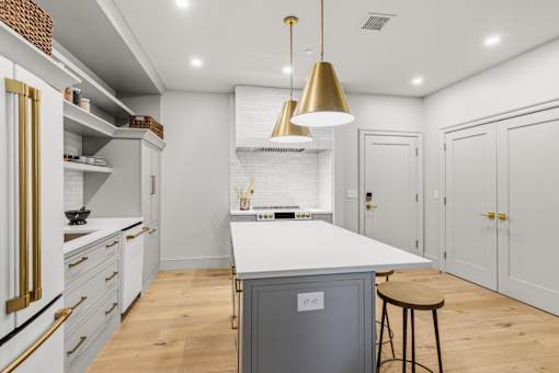 A modern kitchen with a white countertop and wooden floors.