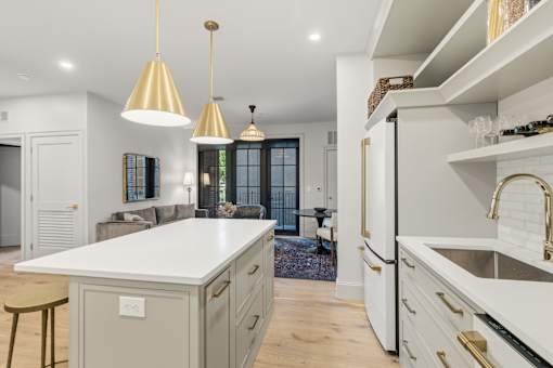 A modern kitchen with a white countertop and gold pendant lights.