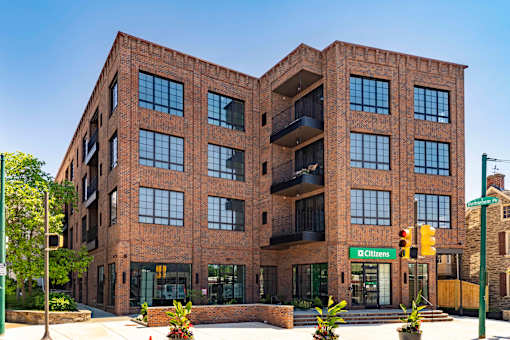 A large brick building with a green street sign in front.