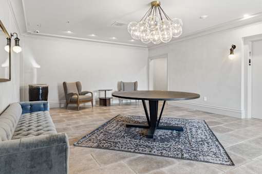 A modern living room with a grey sofa, a round table, and a chandelier.