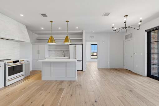 A modern kitchen with wooden floors and white cabinetry.