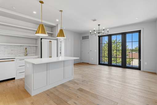 A modern kitchen with a white countertop and wooden floors.