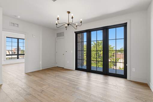 A room with a chandelier, sliding glass doors, and hardwood floors.