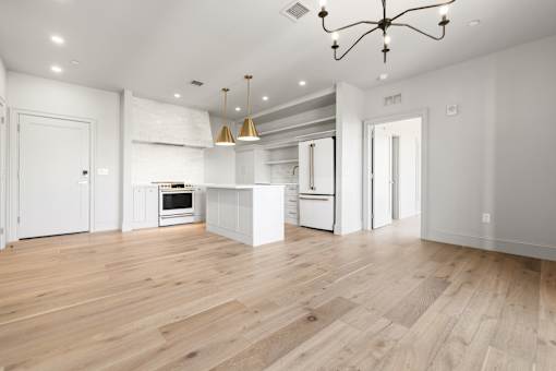 A spacious kitchen with wooden floors and a chandelier.