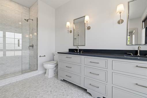 A bathroom with a white tile floor and a black countertop.