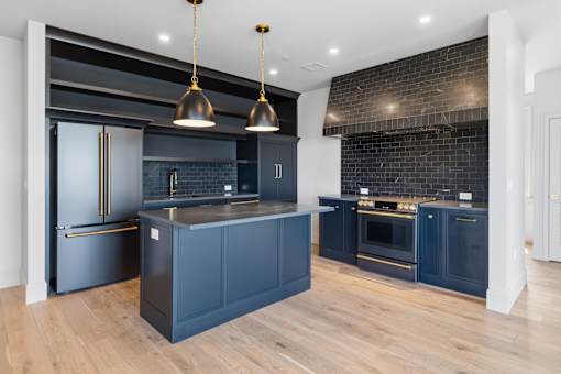 A kitchen with dark blue cabinets and a black refrigerator.