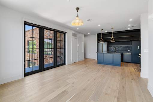 A room with a wooden floor and a kitchen area with a blue island.