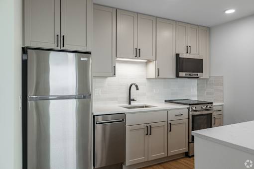 A modern kitchen with a stainless steel refrigerator and white countertops.