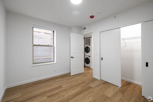A white room with a window and a door leading to a laundry room.