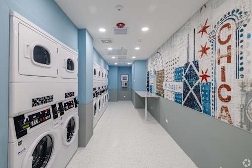 A laundromat with washers and dryers and a mural on the wall.