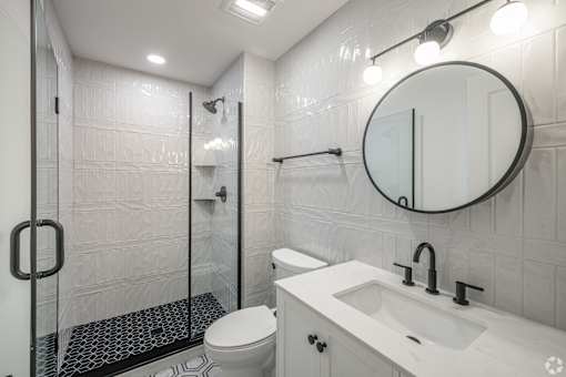 A white bathroom with a toilet, sink, and shower.