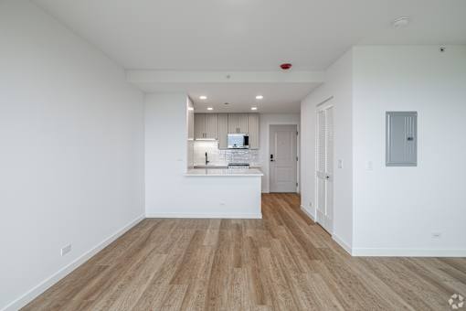 A spacious room with wooden flooring and white walls.
