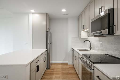 A modern kitchen with white countertops and stainless steel appliances.