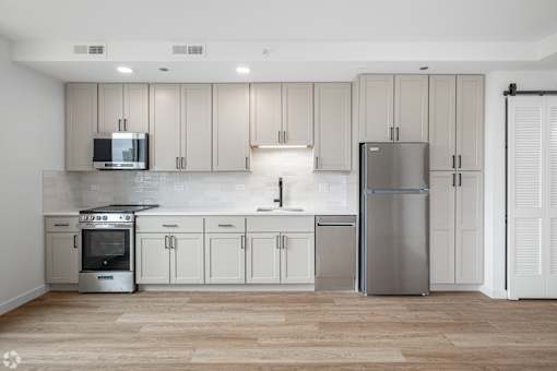 A modern kitchen with wooden floors and stainless steel appliances.