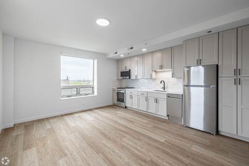 A kitchen with white cabinets and a wooden floor.