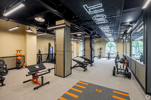 A gym with a variety of equipment including a squat rack, bench press, and a rowing machine.