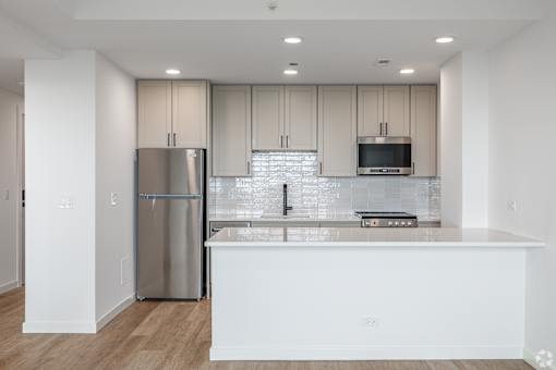 A modern kitchen with a stainless steel refrigerator and white countertops.