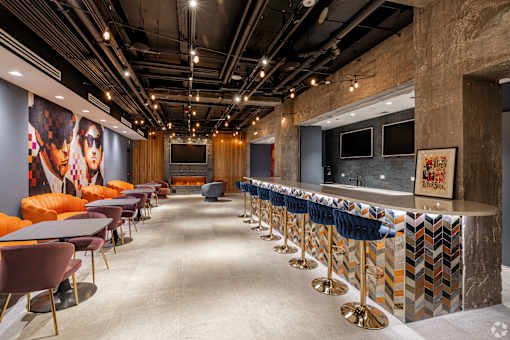 A long row of bar stools with a blue velvet barrier.