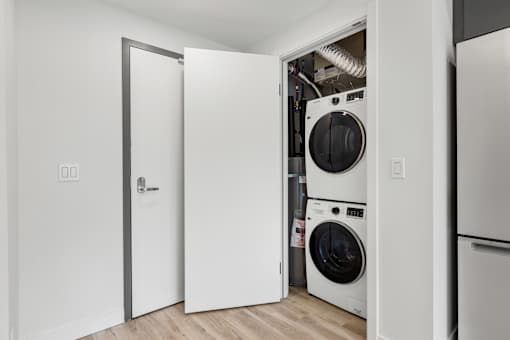 A white door is open to a small laundry room with a washer and dryer.