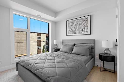 A bedroom with a large bed and a picture on the wall.